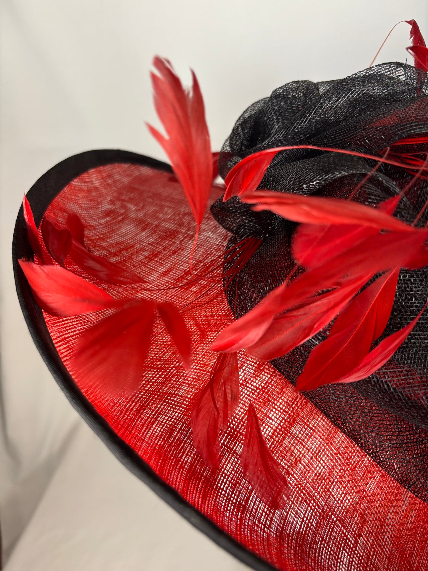 Red and black statement hat with bow and feather design