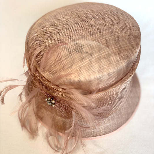 Blush occasion hat with featured feathered design