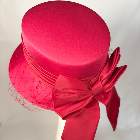 Red occasion hat with layered crown, soft bow and net detail