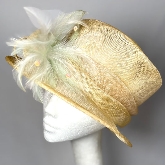 Beige straw occasion hat with layered design and green feather detail