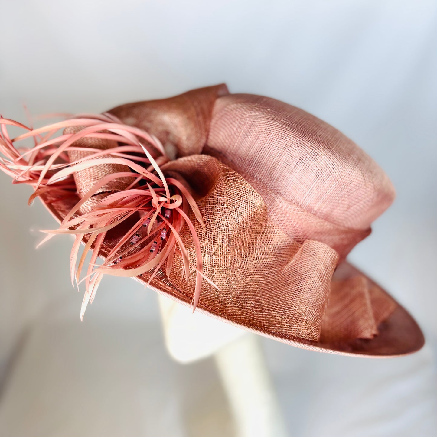 Blush feathered occasion hat with sculpted ribbon detail